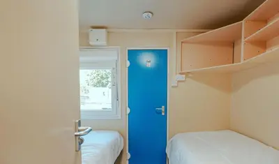 a room with a blue door and two beds at IOMTT Village at Isle of Man TT in Douglas