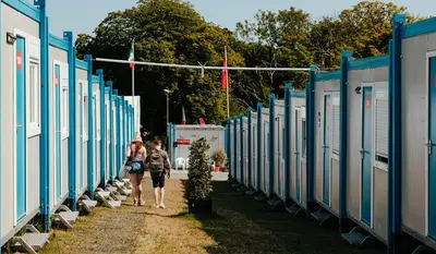 a couple of people walking down a row of houses at IOMTT Village at Isle of Man TT in Douglas