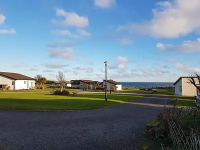 a street with houses and the ocean in the background at 11 Laigh Isle in Isle of Whithorn