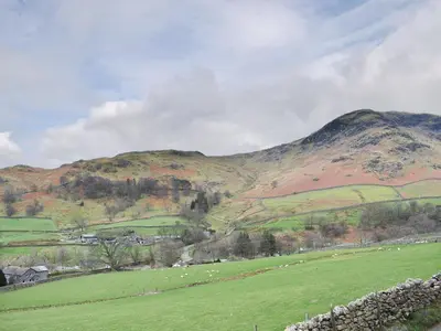 a green field with sheep in front of a mountain at Hovera in Glenridding