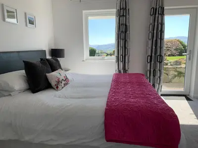 a bedroom with a large bed with a large window at The Bungalows Guesthouse in Threlkeld