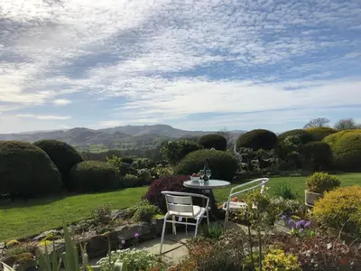 a table and chairs in a garden with mountains in the background at The Bungalows Guesthouse in Threlkeld