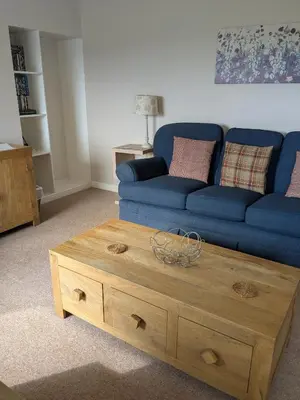 a living room with a blue couch and a wooden coffee table at Boreland Farm in Dunscore