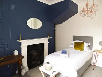 a blue bedroom with a bed and a fireplace at Rosalind House in Carlisle