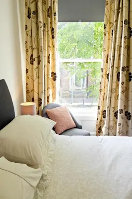 a bedroom with a bed and a window with curtains at Rosalind House in Carlisle