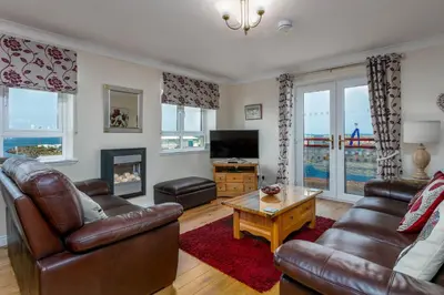 a living room with two leather couches and a fireplace at Arran View - Coorie Doon Stays in Ayr