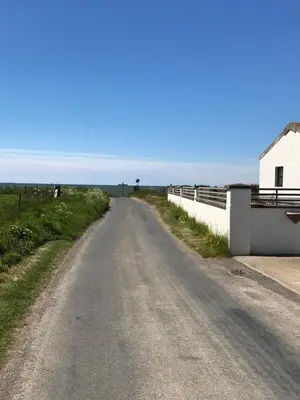 a dirt road next to a fence and a building at Dove cottage in Allonby