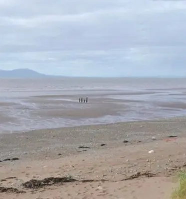 a group of people standing in the water on the beach at Dove cottage in Allonby