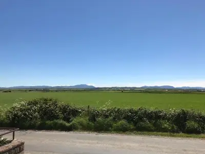 a view of a green field and a road at Sea view cottage in Allonby