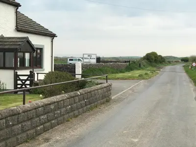 an empty road next to a house with a fence at Sea view cottage in Allonby