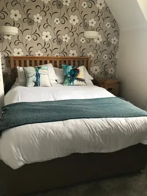 a bedroom with a large bed with a floral wall at Claremont House Keswick in Keswick