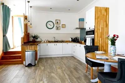 a kitchen with white cabinets and a wooden table at Welch House in Douglas