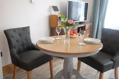 a dining room table with two chairs and a table with wine glasses at Welch House in Douglas
