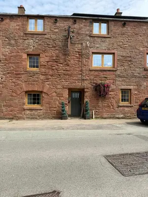 a brick building with a door and a car parked in front at Fairladies Barn Guest House in St Bees
