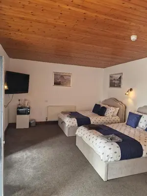 a bedroom with two beds and a wooden ceiling at Fairladies Barn Guest House in St Bees