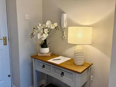a table with a lamp and flowers on it at Kintyre Apartment in Ayr