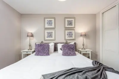 a bedroom with a large white bed with purple pillows at Bay View - Donnini Apartments in Ayr
