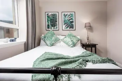 a bedroom with a bed with a green blanket at Bay View - Donnini Apartments in Ayr