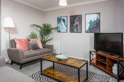 a living room with a couch and a television at Bay View - Donnini Apartments in Ayr