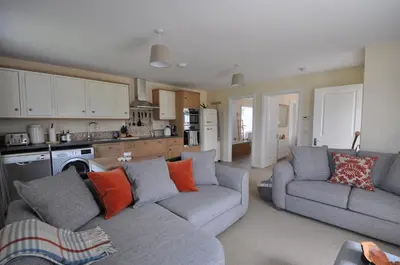 a living room with two couches and a kitchen at No 1 Ramageton at Carnell Estates in Hurlford