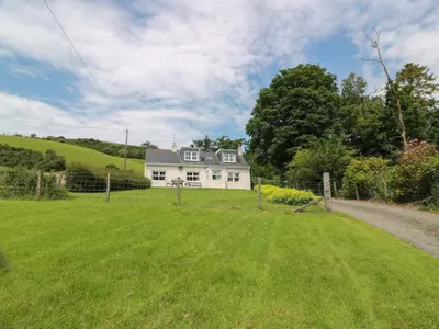 a white house on a hill with a yard at Cairnhill in Girvan
