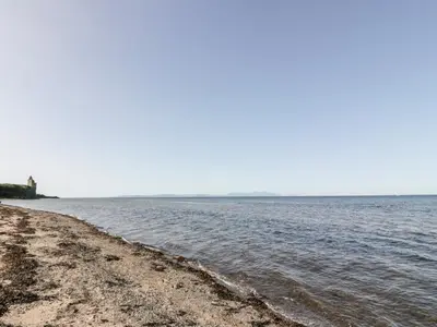 a beach with a lighthouse in the distance at Bright and Beautiful in Ayr