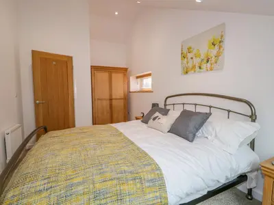 a bedroom with a large white bed with pillows at Coney Garth Cottage in Beckermet