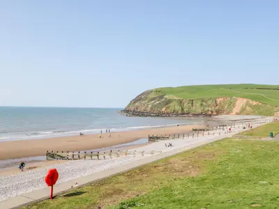 a beach with people walking on the sand and the ocean at Coney Garth Cottage in Beckermet