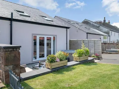 a white house with two potted plants in a yard at Coney Garth Cottage in Beckermet
