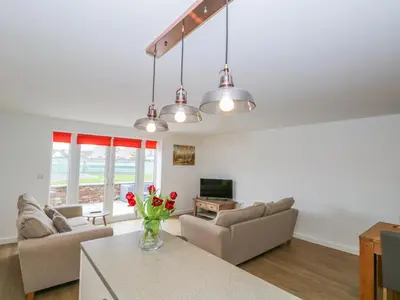a living room with couches and a table at Coney Garth Cottage in Beckermet