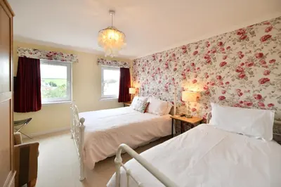 two beds in a bedroom with floral wallpaper at Lochans Lodge in Stranraer