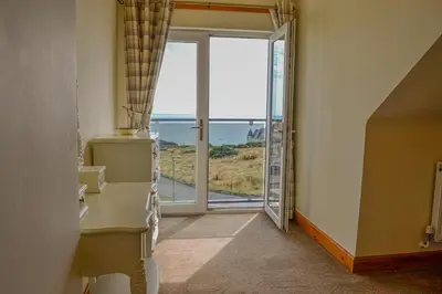a hallway with an open door with a view of the ocean at The Fairways in Portpatrick