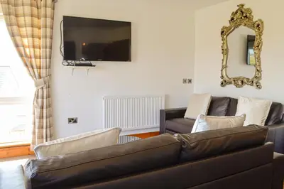 a living room with a couch and a flat screen tv at The Fairways in Portpatrick