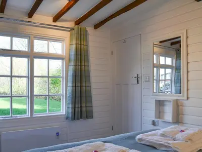 a bedroom with white walls and windows and a bed at Field House Lodge in Borrowdale Valley