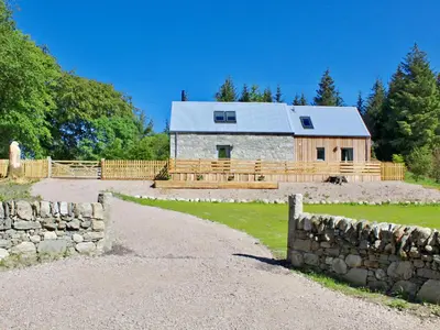 a stone barn with a fence and a stone wall at Ramerish Retreat in Laurieston
