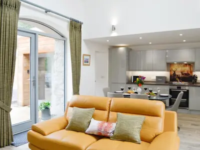 a living room with a couch and a kitchen at Ramerish Retreat in Laurieston