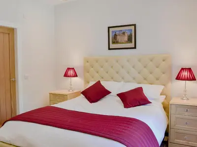 a bedroom with a large bed with red pillows at Smithfield House in Tarbolton