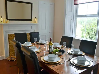 a wooden table with chairs and a bottle of wine at Halleaths Home Farm in Lochmaben