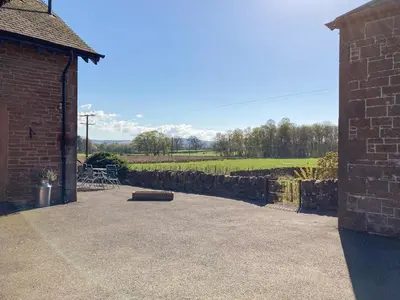 a patio with a stone wall and a brick building at Halleaths Home Farm in Lochmaben
