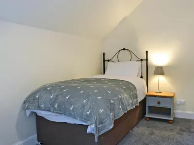 a bedroom with a bed and a lamp on a table at Halleaths Home Farm in Lochmaben