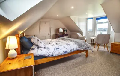 a bedroom with a bed and a table with a lamp at The View in Garlieston