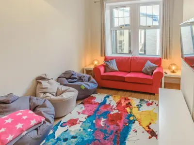 a living room with a red couch and a rug at Blair Terrace in Portpatrick