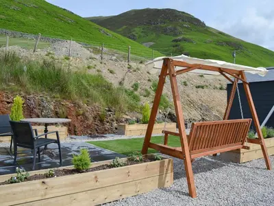 a swing with an umbrella and a table at The Rocking Lodge in Threlkeld