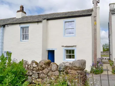 a white house with a blue door and a stone fence at Springlea Cottage in Dean