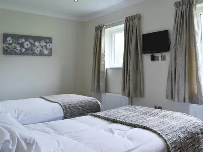 a bedroom with two beds and a tv on the wall at Lucy's At The Grange - Uk11519 in Mockerkin