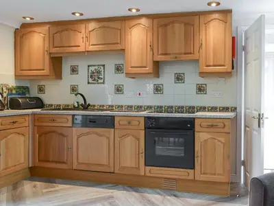 a kitchen with wooden cabinets and a black dishwasher at Lorna's At The Grange - Uk11565 in Mockerkin