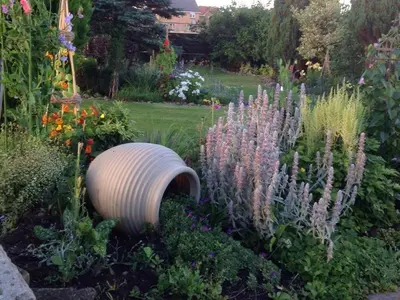 a garden with flowers and a barrel in the middle at Woodend in Maxwelltown