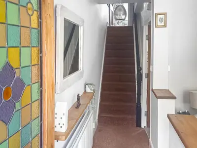 a hallway with a staircase with a mirror and a window at Wanderers Rest in Keswick