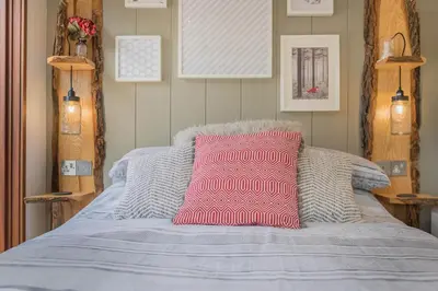 a bed with a pink pillow on top of it at Dobby Lodge in Bassenthwaite