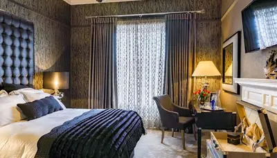 a hotel room with a bed and a desk and a window at Ram Lodge in Moffat